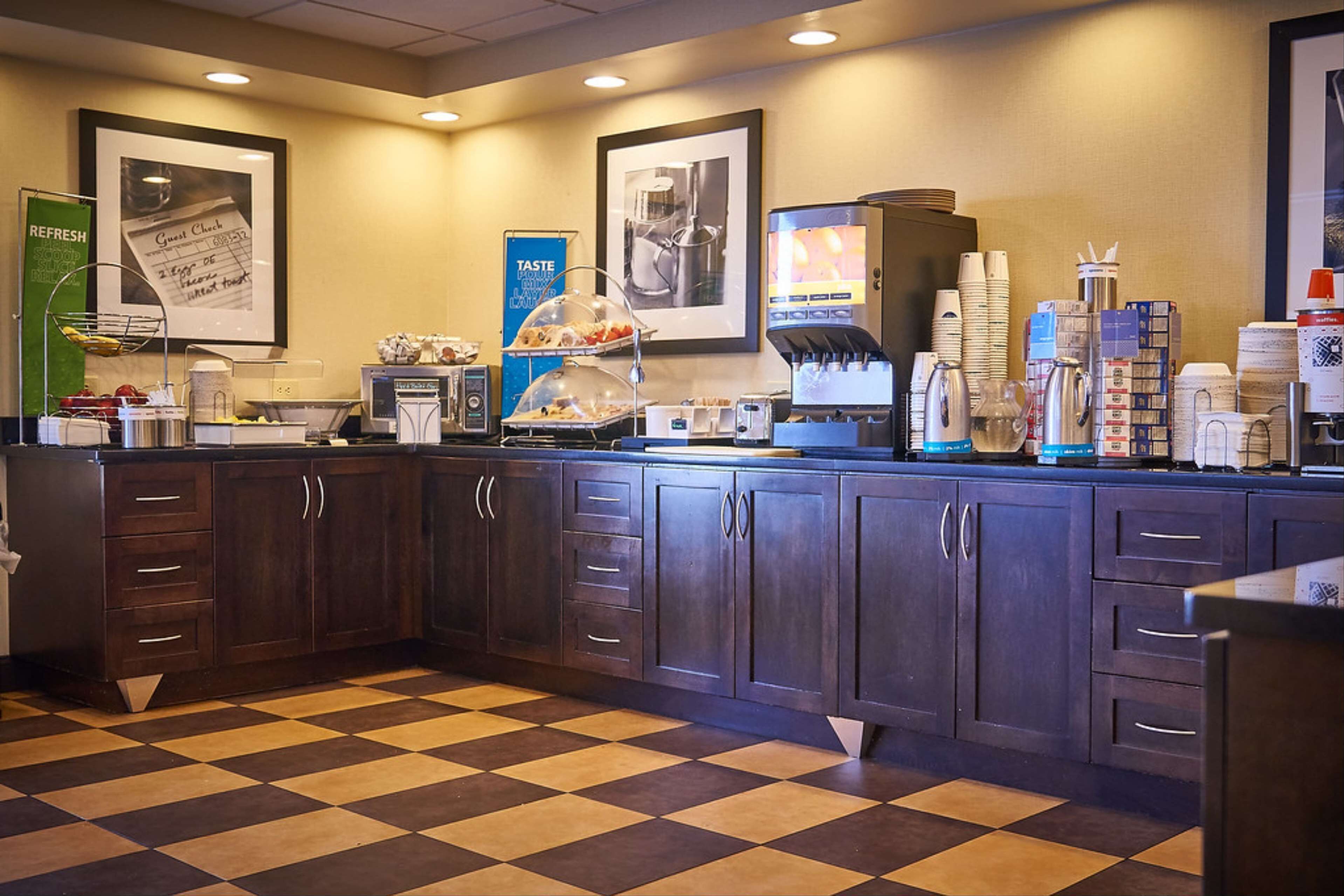 Una barra de desayuno con suelo de cuadros, una máquina de café y un panel con el menú.