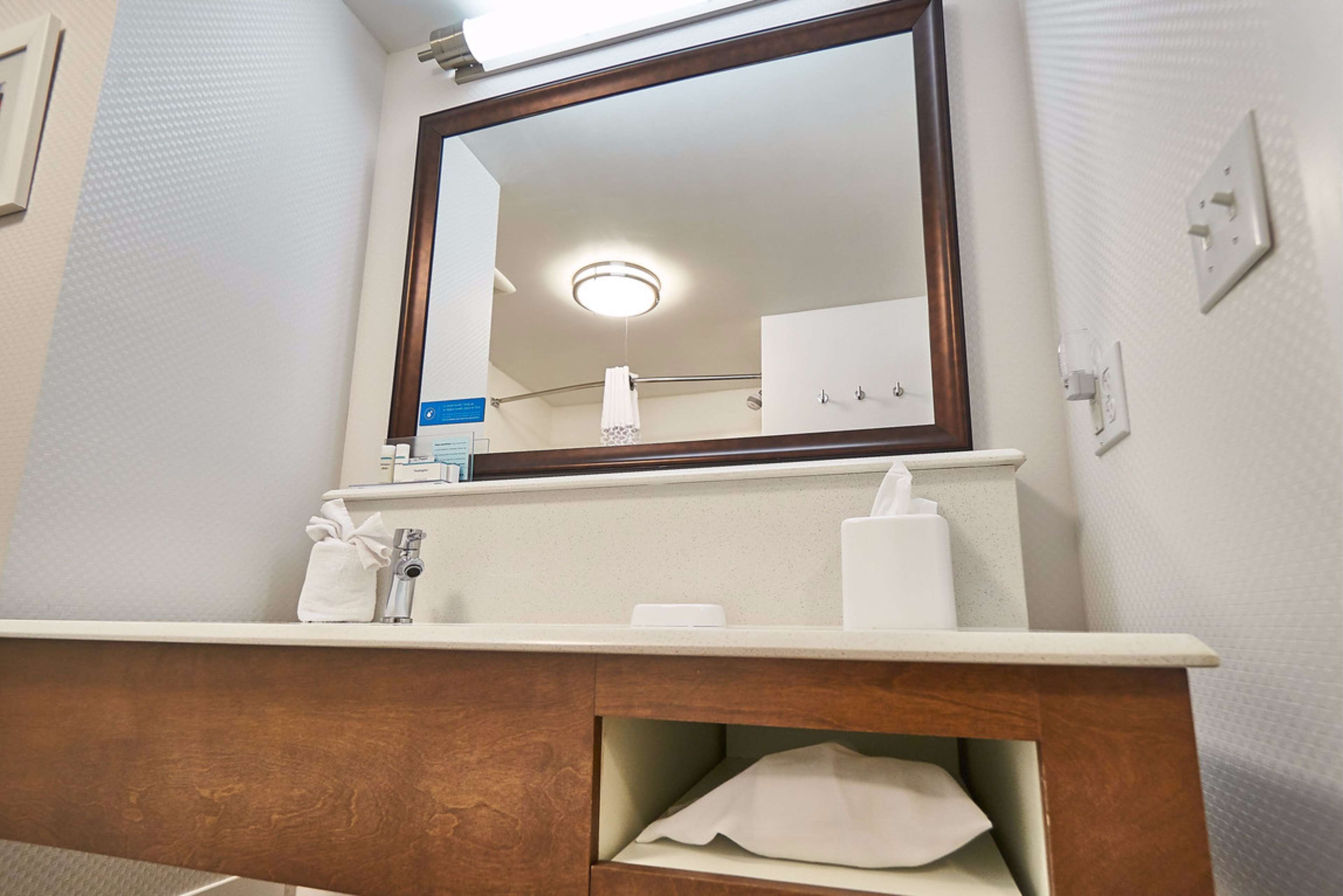 A bathroom with a wooden vanity, a mirror, and a towel rack.
