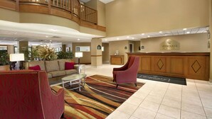 A lobby with a reception desk, a red armchair, a sofa, and a coffee table. - Wingate Inn Chattanooga (Chattanooga)