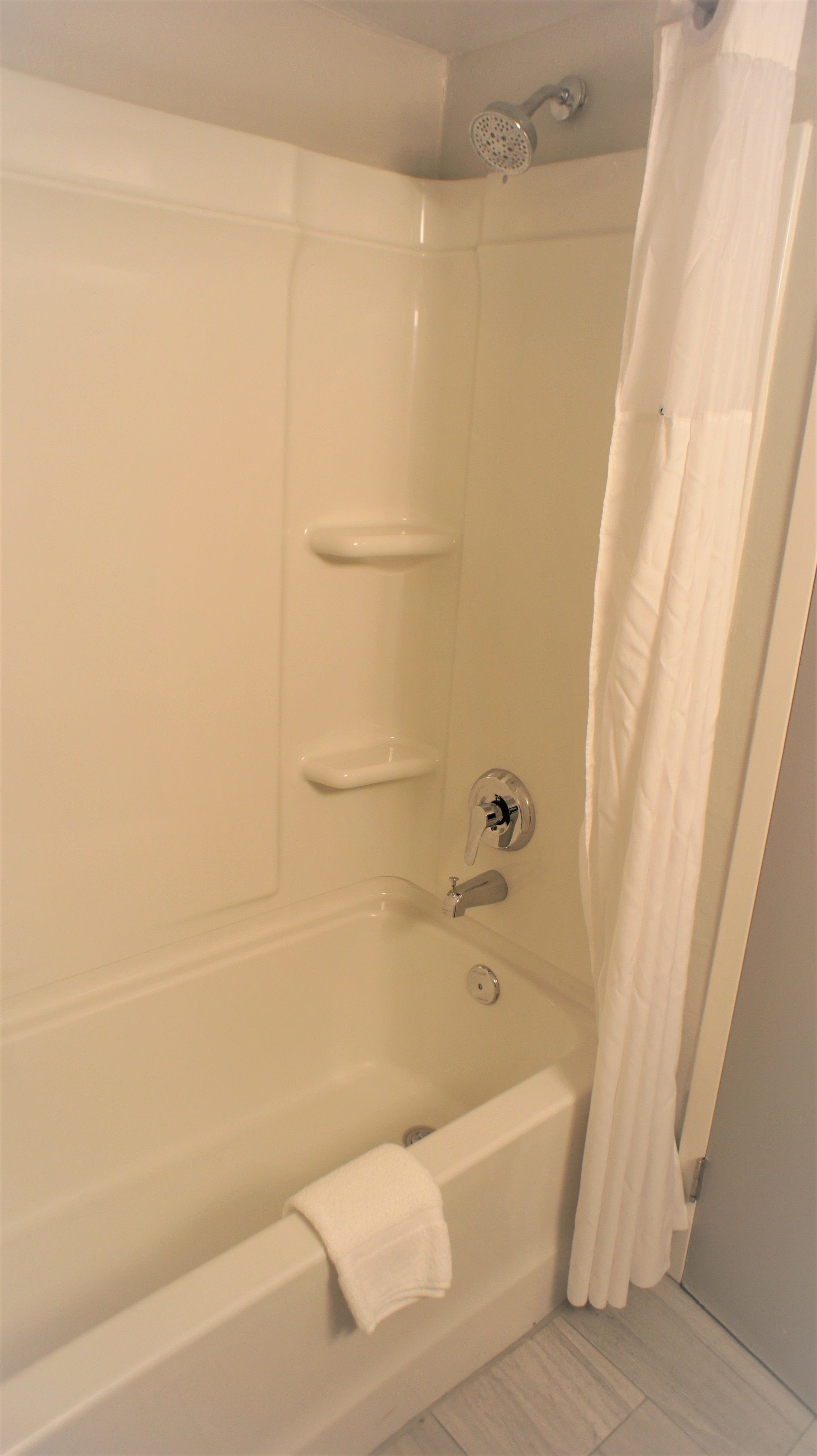 A white bathtub with a showerhead, a towel rack, and a shower curtain.