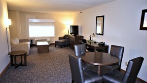 A hotel room with a sofa, a small table, a desk with a chair, a TV, and a lamp. - Wingate Inn Chattanooga (Chattanooga)