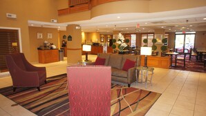 A hotel lobby with a reception desk, seating area, and a view of the dining area. - Wingate Inn Chattanooga (Chattanooga)
