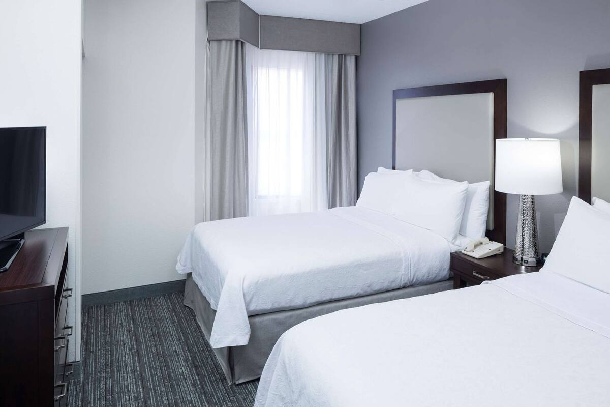Een hotelkamer met twee bedden, een televisie, een lamp en een telefoon op een nachtkastje.