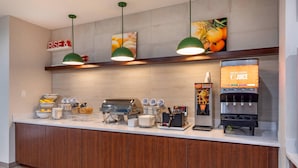 A breakfast bar with a coffee machine, juice dispenser, and various food items. - Comfort Inn - Weatherford (Weatherford)