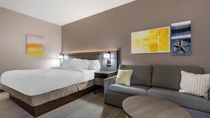 A modern hotel room with a large bed, a sofa, a small table, and artwork on the walls. - Comfort Inn - Weatherford (Weatherford)