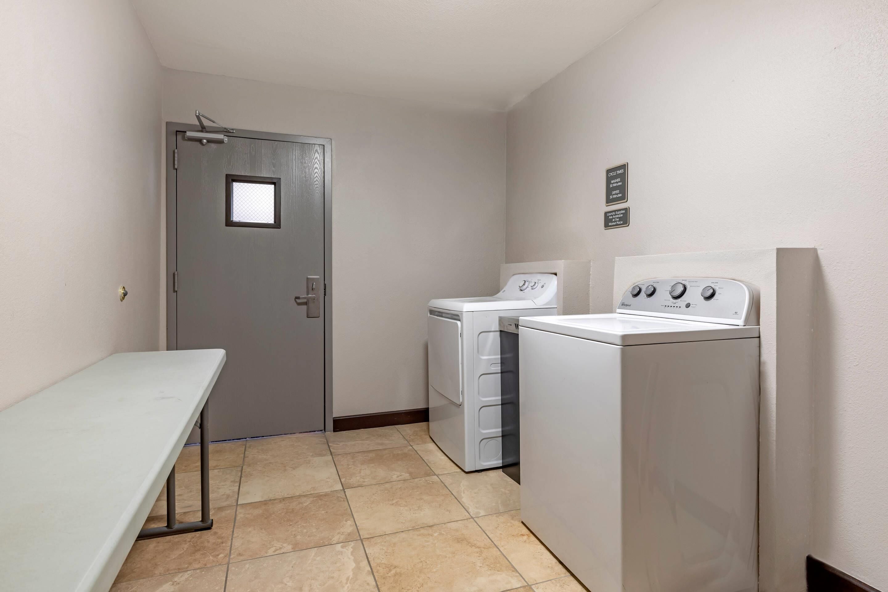 A laundry room with a bench, two washing machines, and a door with a small window.