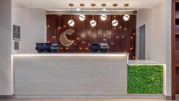 A reception desk with two computers, a wooden wall with a crescent moon design, and hanging pendant lights. - Comfort Inn - Weatherford (Weatherford)