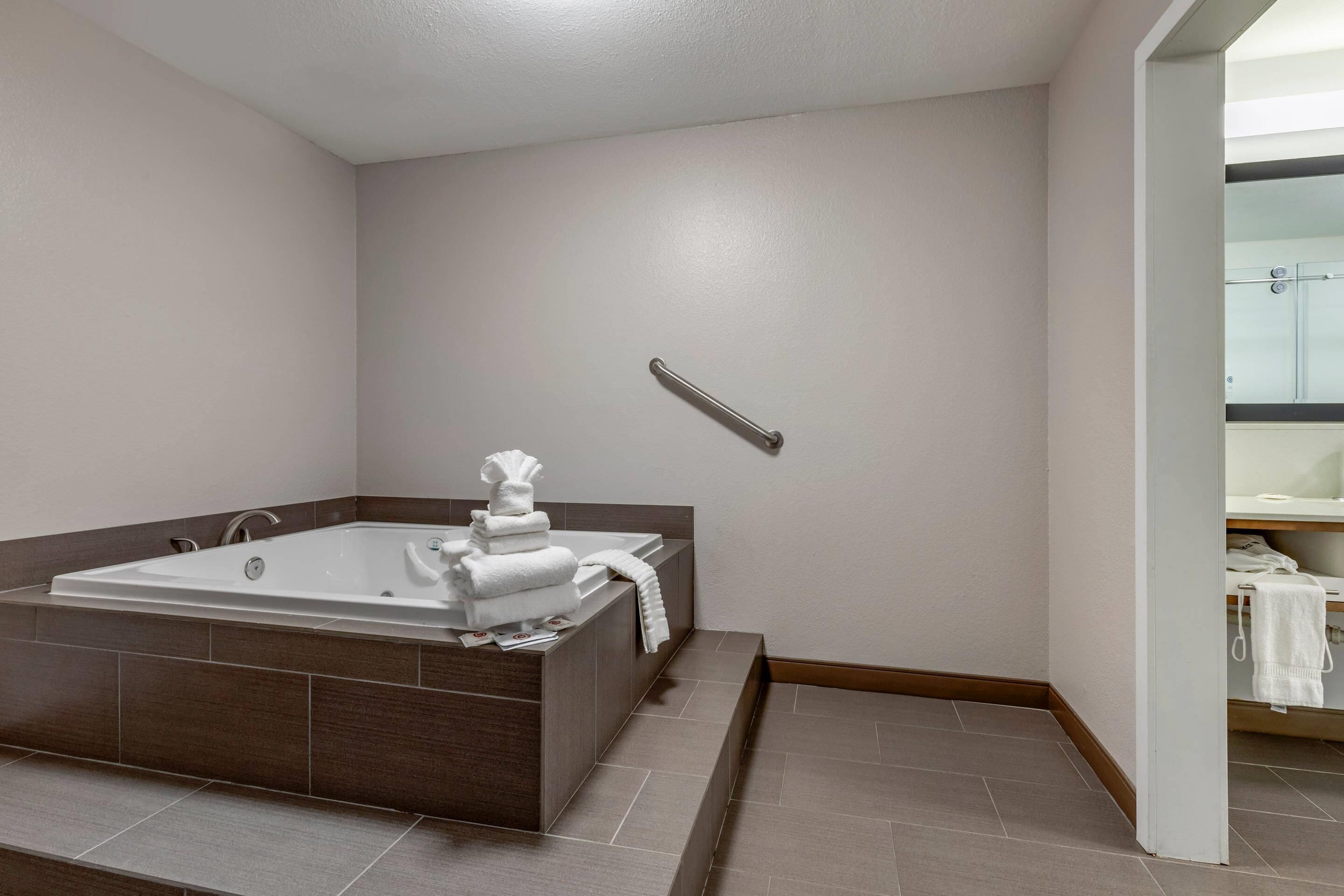 A modern bathroom with a large bathtub, a towel rack, and a shower area.