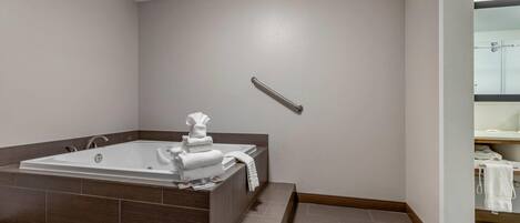 A modern bathroom with a large bathtub, a towel rack, and a shower area.