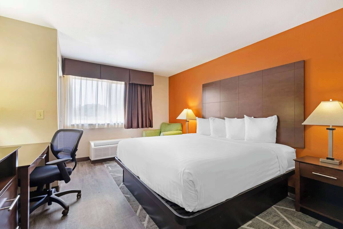 Ein Hotelzimmer mit einem großen Bett, einem Schreibtisch, einem Stuhl und einer Lampe.