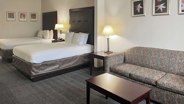 A hotel room with two beds, a sofa, a small table, and a lamp. - Quality Inn & Suites Houston Northwest - Cypress (Houston)