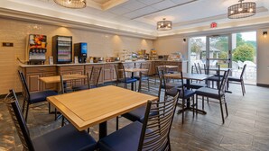 A restaurant with multiple tables and chairs, a counter with a coffee machine, and a sign indicating an exit. - Best Western Plus Hudson I-94 (Hudson)