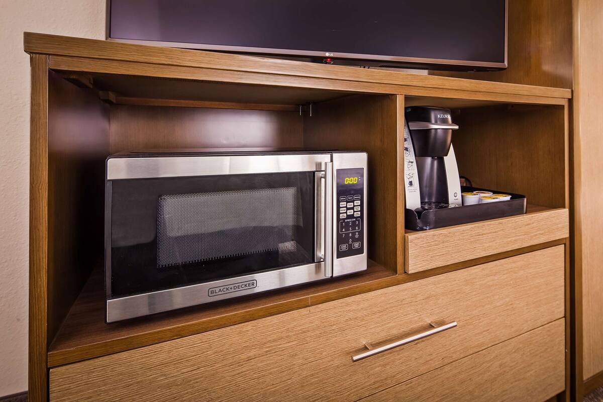 A compact kitchenette with a microwave, coffee maker, and a refrigerator.