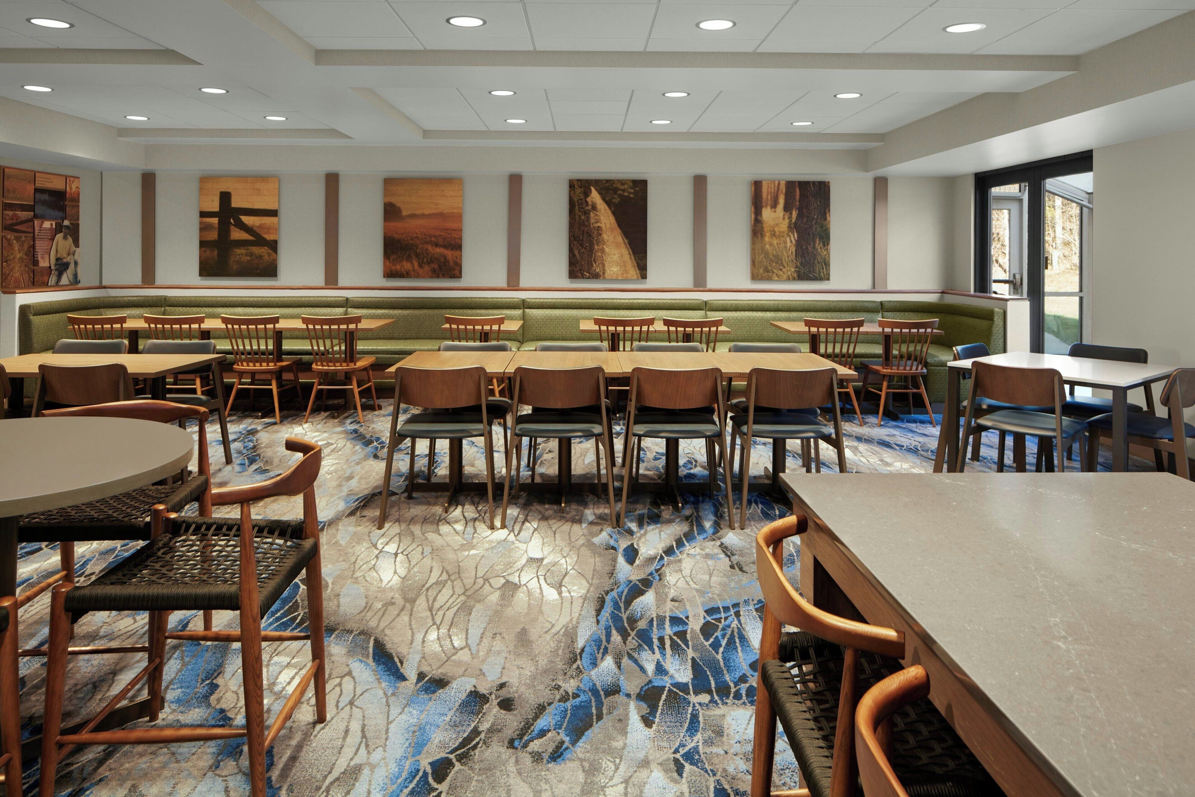 Un vaste espace dédié à la salle à manger, avec des banquettes et des tables, un sol en marbre et des œuvres d’art accrochées aux murs.