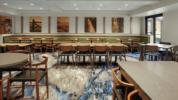 A spacious dining area with booths and tables, featuring a marble floor and artwork on the walls.