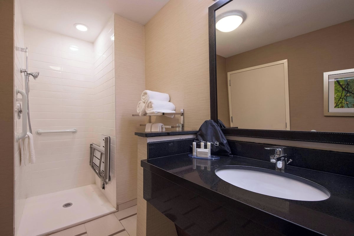 Une salle de bain moderne avec une douche à l’italienne, un lavabo avec un miroir et un porte-serviettes.