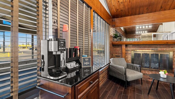 A modern kitchen with a coffee station, a fireplace, and a view of the outside. - Rodeway Inn Dickson (Dickson)