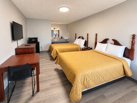 Habitación de hotel con dos camas, un escritorio, un televisor y una kitchenette.
