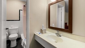 A bathroom with a toilet, sink, and mirror. - Rodeway Inn Dickson (Dickson)