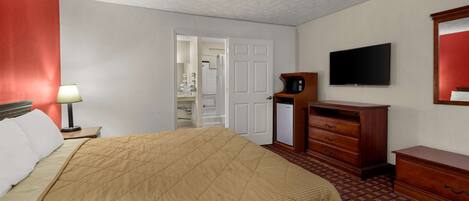 A hotel room with a bed, a television, a microwave, and a dresser.
