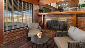 A cozy living area with a fireplace, brick walls, and a view of the street. - Rodeway Inn Dickson (Dickson)