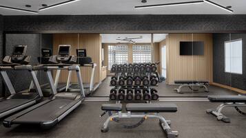 A modern gym with treadmills, dumbbells, and weight benches.