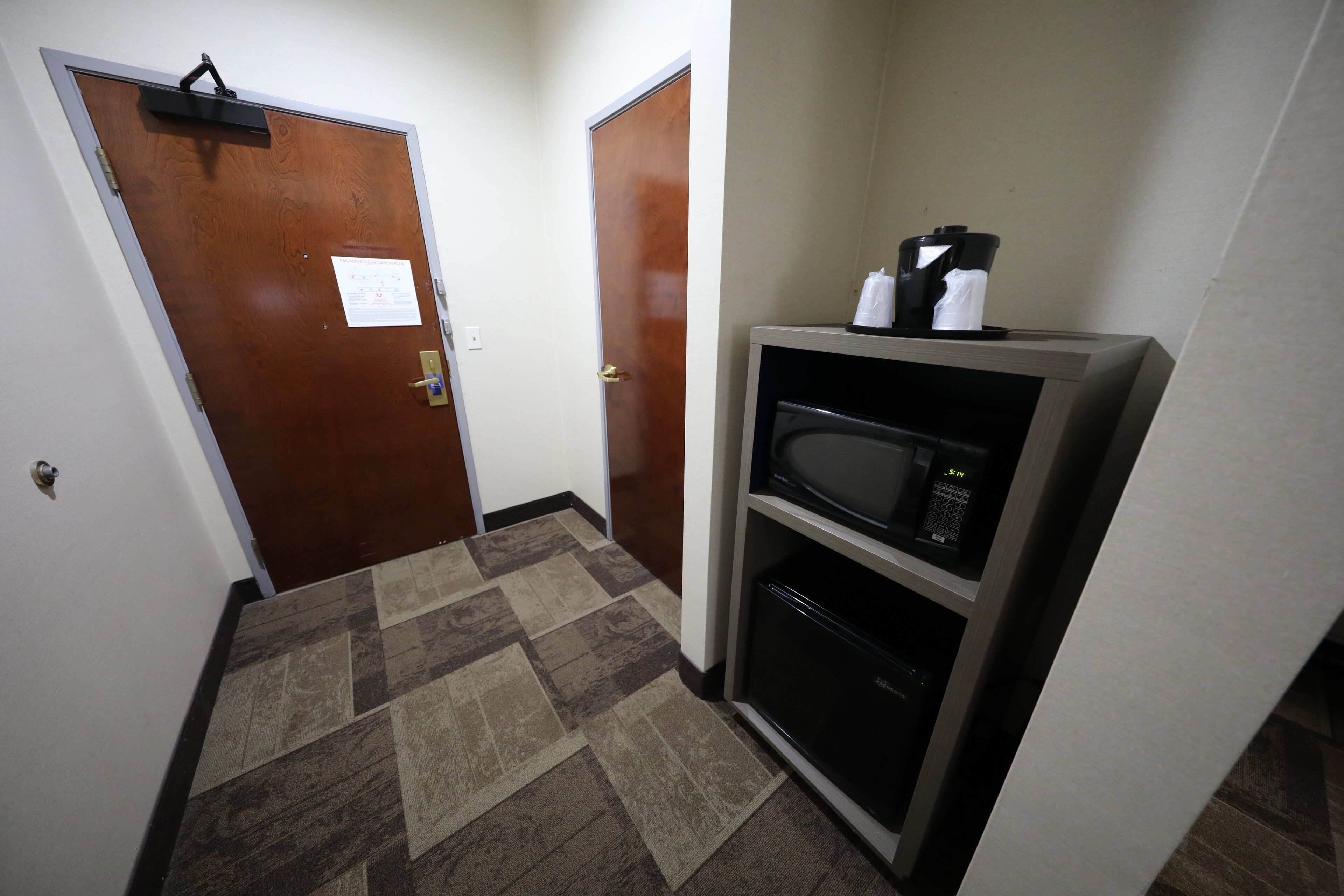 A hallway with patterned carpet, a microwave, and a refrigerator.