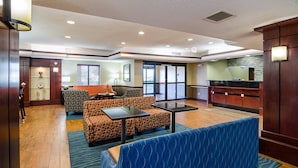 A hotel lobby with a seating area, a reception desk, and a kitchenette.