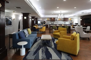 Una sala de estar moderna con un sofá azul, sillones amarillos y una mesa de centro.