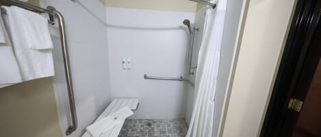Un espace douche équipé d’une barre d’appui, d’un porte-serviettes blanc et d’un rideau de douche.