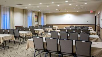 Uma sala de conferência com mesas e cadeiras, um tapete estampado e cortinas nas janelas.