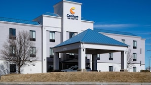 A modern Comfort Inn & Suites building with a covered parking area, a flat roof, and a clear blue sky.