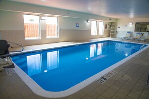 Piscina interior con agua cristalina, paredes con azulejos y ventanas que dejan entrar luz natural.