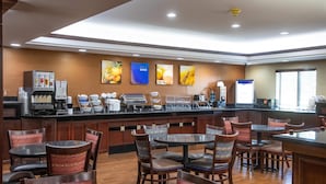 A hotel kitchen with a coffee station, seating area, and artwork on the walls.