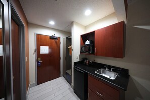 Cocina pequeña con microondas, lavabo y armarios.