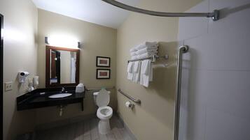 A bathroom with a toilet, sink, mirror, towel rack, and hand dryer.