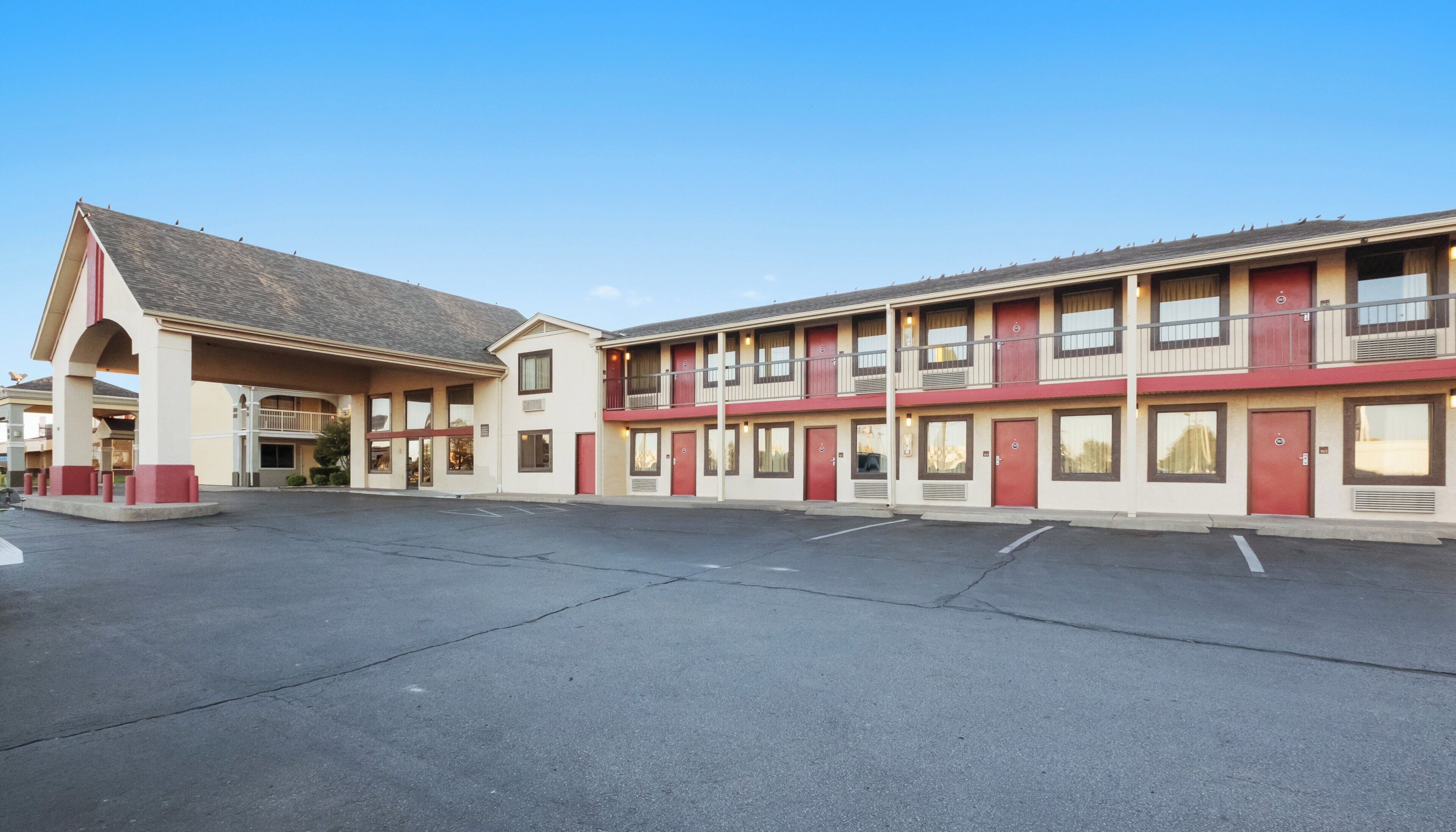 A motel with a central parking lot and a two-story building with multiple rooms.