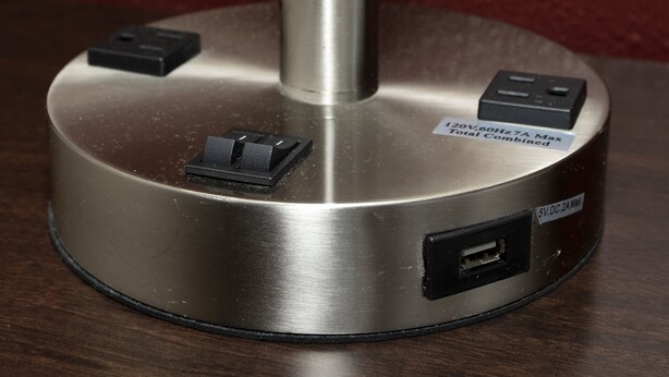 A power strip with multiple outlets and USB ports, mounted on a metallic base. - Red Roof Inn Oklahoma Airport – I-40 W/Fairgrounds (Oklahoma City)