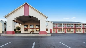 A hotel with a central entrance, a parking lot, and a multi-story building with balconies. - Red Roof Inn Oklahoma Airport – I-40 W/Fairgrounds (Oklahoma City)