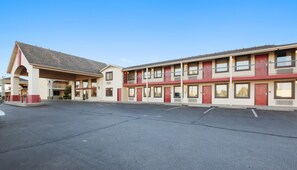 Un motel doté d’un parking central et de plusieurs chambres avec balcon.