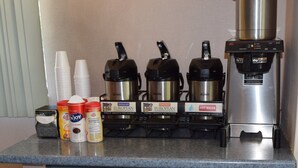 A coffee station with three coffee makers, disposable cups, and various coffee creamer options. - Red Roof Inn Oklahoma Airport – I-40 W/Fairgrounds (Oklahoma City)
