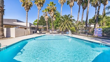 Een seizoensgebonden buitenzwembad, ligstoelen bij het zwembad