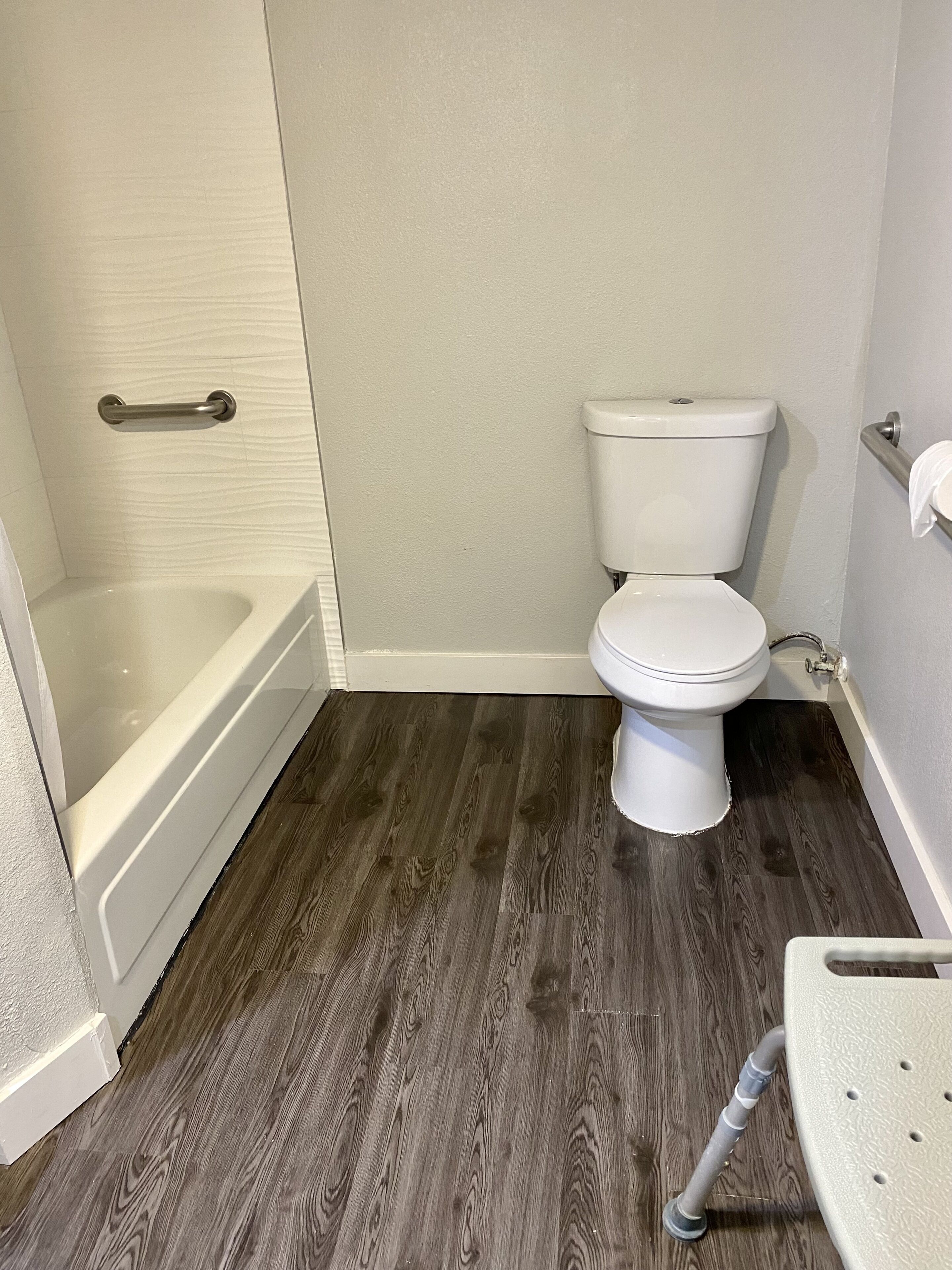 Une salle de bain avec des toilettes blanches, une baignoire et un plancher en bois.