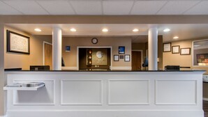 A reception area with a white reception desk, framed certificates on the wall, and a clock above the desk.