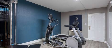 A home gym with a treadmill, elliptical, and weight bench.