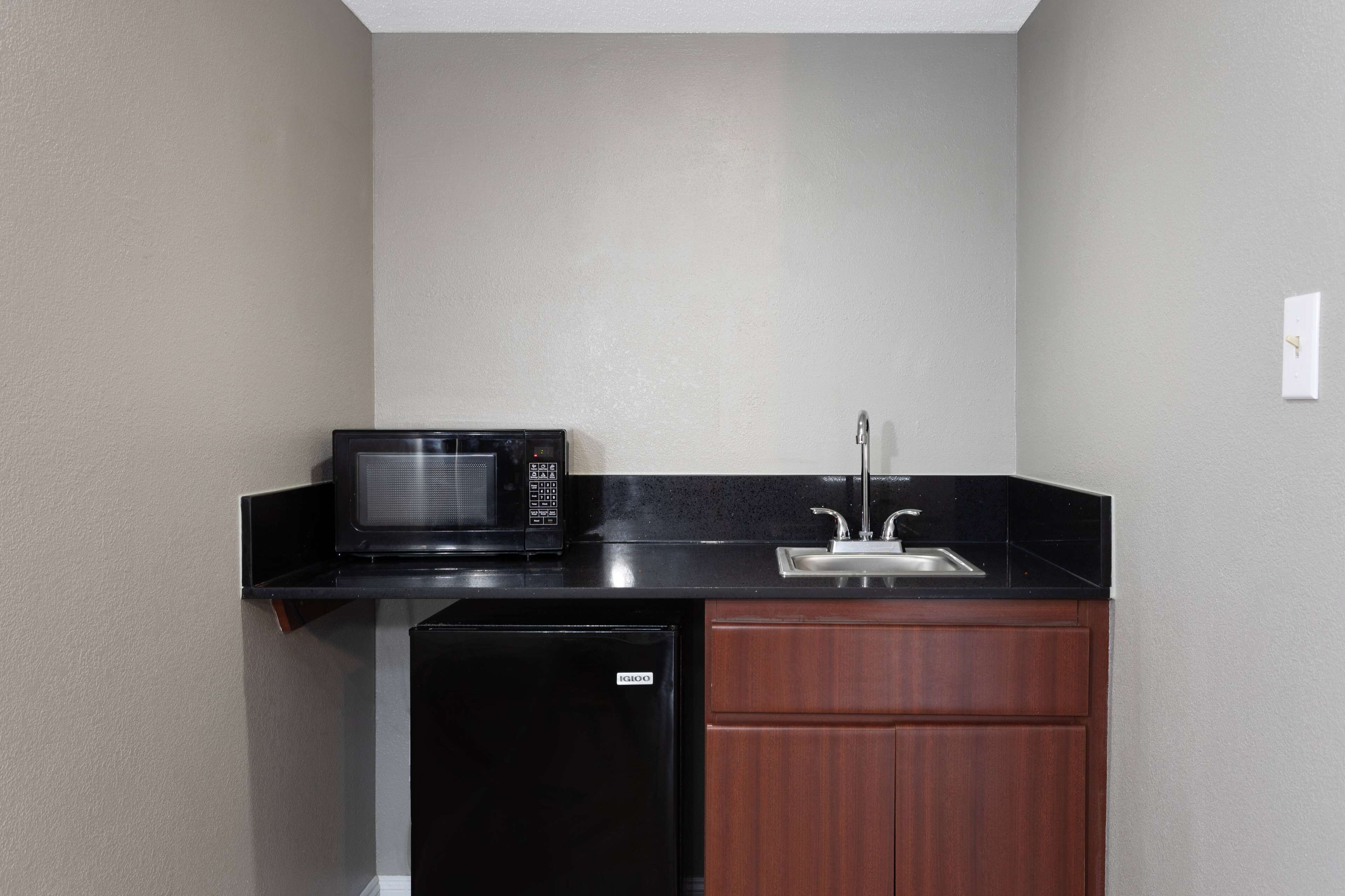 A compact kitchenette with a black microwave, a sink, and a small refrigerator.