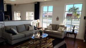 Een ruime woonkamer met twee banken, een salontafel en een fauteuil. Er zijn grote ramen met uitzicht op het omliggende landschap.