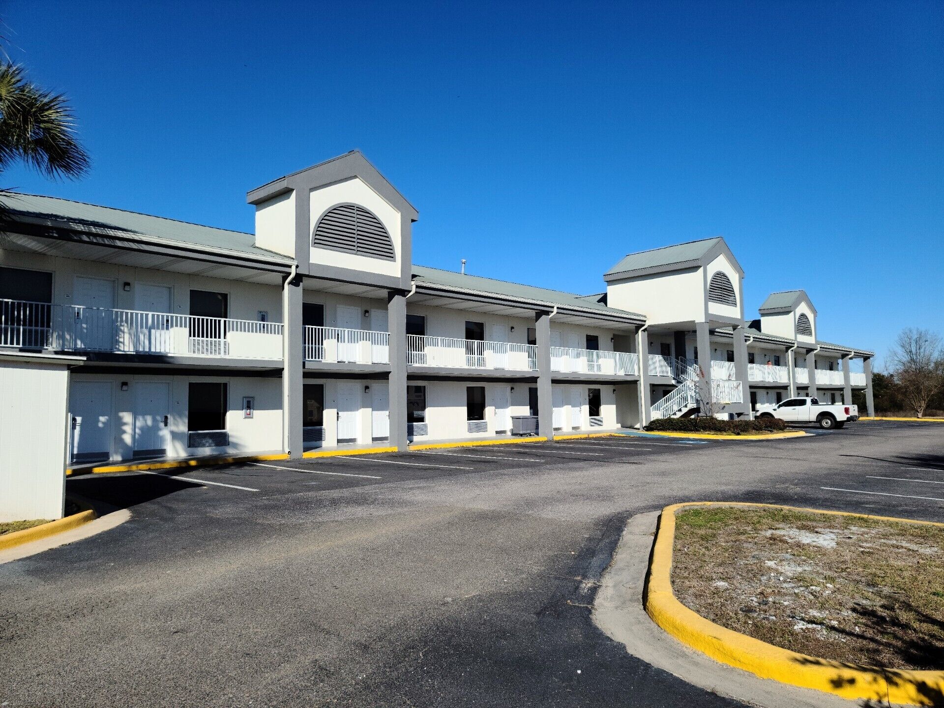 Un motel con diversi piani, balconi e un parcheggio.