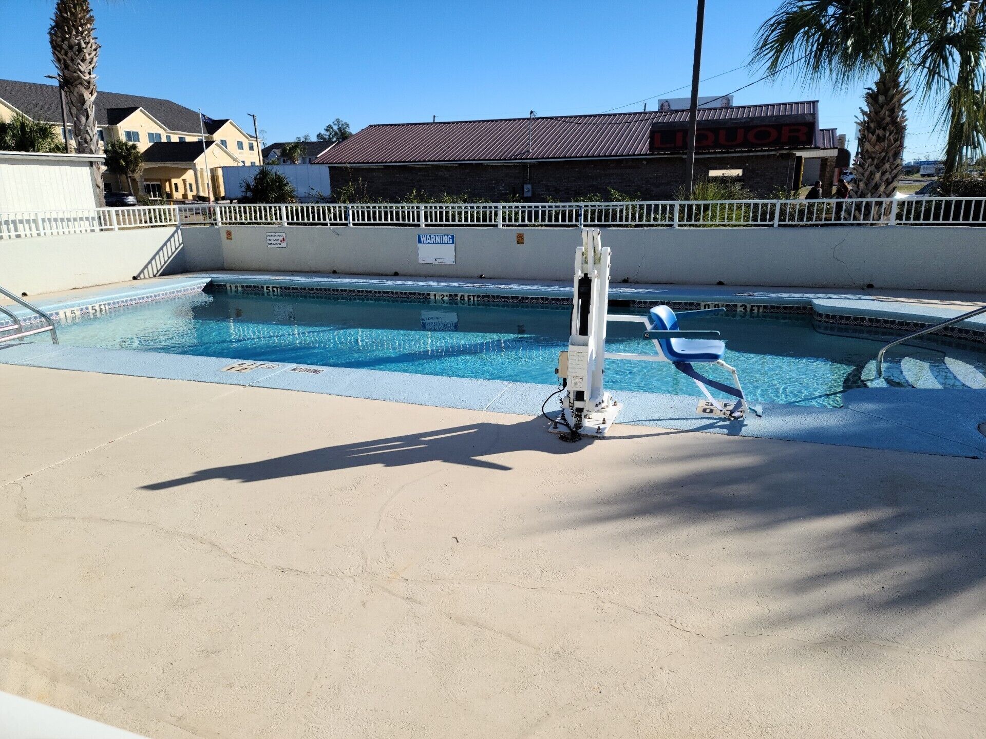 A swimming pool with a diving board, a lifeguard chair, and a pool ladder.