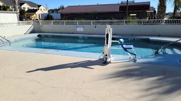 A swimming pool with a diving board, a lifeguard chair, and a pool ladder.